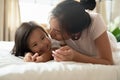 Close up Asian mother kissing little daughter, lying on bed Royalty Free Stock Photo