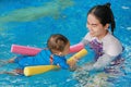 Close-up Asian mother teaching baby boy in swimming pool with noodle foam Royalty Free Stock Photo