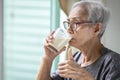Close up,Asian senior woman drinking fresh milk from the glass,healthy elderly holding glass of milk,old people showing thumb up Royalty Free Stock Photo