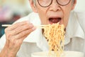 Close up,Asian senior woman opening her mouth to eat instant noodles,junk food,old elderly eating instant noodles,dangers of high