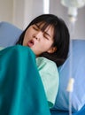 Close-up of an asian sick female patient covered with a blanket lying on hospital bed having intravenous drip saline solution, Royalty Free Stock Photo