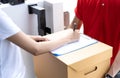 Close-up of a Asian woman appending signature sign on clipboard after accepting receive boxes from delivery man, woman sign on the