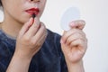 Asian woman is applying red lipstick on her lips Royalty Free Stock Photo