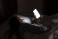 Close up of Asian woman chatting and surfing on the internet with smartphone late at night in bed. Bored and sleepless in dark Royalty Free Stock Photo