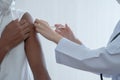 Close up on Asian woman doctor hand holding syringe to injections or vaccines to upper arm of African dark skinned man