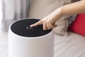 Close-up Asian woman hand, pressing a button on air purifier machine in a bedroom. Protect PM 2.5 dust and air pollution concept.