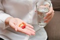 Close up Asian woman holding pill and a glass of water