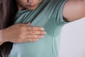 Close-up asian woman with hyperhidrosis sweating. Young asia woman with sweat stain on her clothes against grey background. Royalty Free Stock Photo