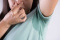 Close-up asian woman with hyperhidrosis sweating. Young asia woman with sweat stain on her clothes against grey background. Royalty Free Stock Photo