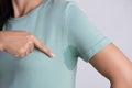 Close-up asian woman with hyperhidrosis sweating. Young asia woman with sweat stain on her clothes against grey background. Royalty Free Stock Photo