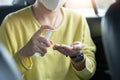 Close up Asian woman Passenger in yellow shirt with surgical mask spraying sanitizer alcohol on her palms and her hands for Royalty Free Stock Photo