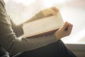 Close-up of an Asian woman reading an old book in the corner of a university library. With golden light shining through the glass Royalty Free Stock Photo