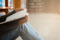 Close-up of an asian woman reading an old book in the corner of a university library. With golden light shining through the glass Royalty Free Stock Photo