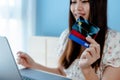 Close-up of an Asian woman sitting holding three credit cards, sitting and placing an order online, Royalty Free Stock Photo