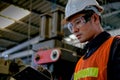 Close up Asian worker or technician man write on document paper in factory in front of machine