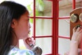 Close Up Asian Young Girl Child Using Dial Telephone Booth. Kid Call On The Retro Vintage Red Phone Booth, Side View