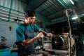 Close-up of Asian young man`s face, with a serious expression on the controls, and working of a lathe, in his small factory, whic Royalty Free Stock Photo