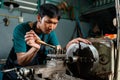 Close-up of Asian young man`s face, with a serious expression on the controls, and working of a lathe, in his small factory, whic Royalty Free Stock Photo