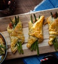 Close up of asparagus and prosciutto pastry bundles fresh out of the oven with two glasses of soda.