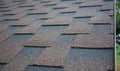 A close-up of asphalt shingles installation on the edge of the roof. Brown architectural asphalt shingles background, texture Royalty Free Stock Photo