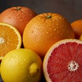 A close-up of assorted citrus fruits. A grapefruit and orange are sliced open