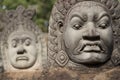 Close up of Asuras demons statues in a row at the Bayon Temple entrance gate