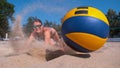 CLOSE UP: Athletic girl playing volleyball dives into the sand to reach the ball Royalty Free Stock Photo