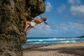 CLOSE UP: Athletic rock climber scales a massive boulder on the rugged beach.