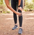 Close up of an athletic young woman holding her knee in pain while exercising outdoors. Active woman wearing running Royalty Free Stock Photo