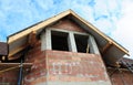 A close-up on attic, mansard and roofing construction with unfinished soffit, eaves, fascia and window of a brick house Royalty Free Stock Photo