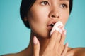 Close up attractive Asian brunette girl sensually posing with make up sponge over colorful background isolated