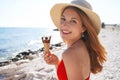Close-up of attractive bikini woman with hat holding ice cream cone italian gelato turns around to the camera on the beach on Royalty Free Stock Photo