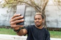 Close up of attractive dark-skinned man making selfie on mobile phone.