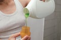 Close up of attractive female pouring liquid green gel into bottle cap. Woman pours liquid washing gel into plastic cap. The Royalty Free Stock Photo
