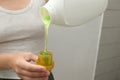 Close up of attractive female pouring liquid green gel into bottle cap. Woman pours liquid washing gel into plastic cap. The Royalty Free Stock Photo