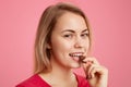 Close up of attractive girl eats delicious dessert, looks mysteriously at camera, enjoys sweet chocolate, has minimal makeup, Royalty Free Stock Photo