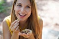 Close-up of healthy woman eating Brazil nuts outoor. Looks to the side