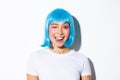 Close-up of attractive party girl in blue wig, showing tongue and winking happy, celebrating halloween, standing over