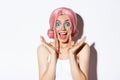 Close-up of attractive party girl in pink wig and bright makeup looking excited and smiling, standing over white