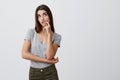 Close up of attractive serious caucasian girl with dark long hair in casual gray shirt and jeans holding hand near Royalty Free Stock Photo