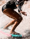 Close-up of attractive tanned legs of sporty woman who actively riding on surf style wakeboard. Royalty Free Stock Photo