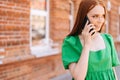 Close-up of attractive young woman talking on mobile phone walking on city street in sunny summer day Royalty Free Stock Photo