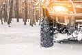 Close-up ATV 4wd quad bike in forest at winter. 4wd all-terreain vehicle stand in heavy snow with deep wheel track. Seasonal extre Royalty Free Stock Photo