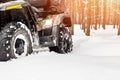 Close-up ATV 4wd quad bike in forest at winter. 4wd all-terreain vehicle stand in heavy snow with deep wheel track. Seasonal Royalty Free Stock Photo