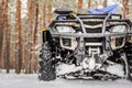 Close-up ATV 4wd quad bike in forest at winter. 4wd all-terreain vehicle stand in heavy snow with deep wheel track. Seasonal extre Royalty Free Stock Photo