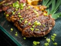 Close-up Australian sliced medium rare wagyu grilled beef steak top with sliced spring onion on glass plate on dark background. Royalty Free Stock Photo