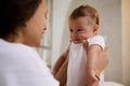 Close-up authentic portrait of an adorable baby boy smiling to his mother holding him in arms. Babyhood and Infancy time