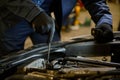 Close-up auto mechanic hands with wrench repairing car in the garage of a repair shop Royalty Free Stock Photo