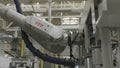 Close up of automatic robotic arm inserting detail into the mechanism at the production line of a car factory. Scene