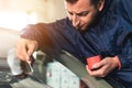 Close up Automobile glazier worker fixing and repair windscreen or windshield of a car in auto service station garage Royalty Free Stock Photo